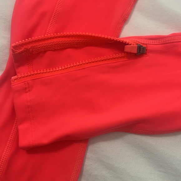Fabletics bright orange leggings with zipper at the ankle and side pockets. - Picture 2 of 4